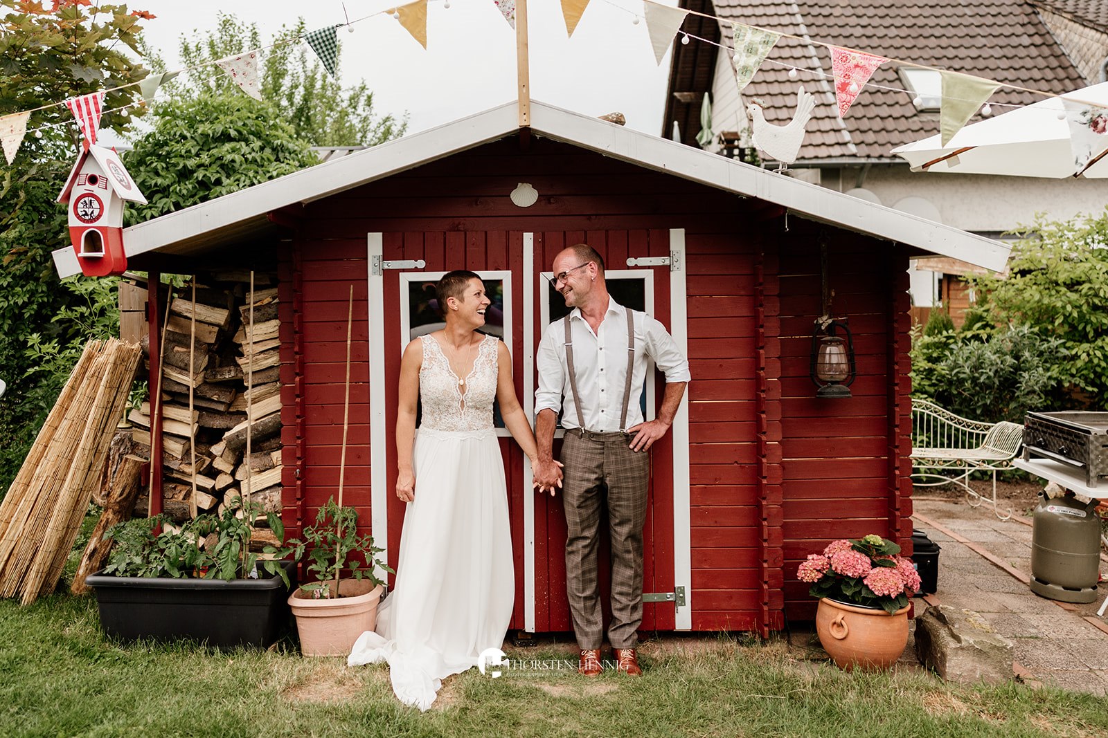 Hochzeitsportrait von Melanie und Jochen vor einem roten Gartenhaus